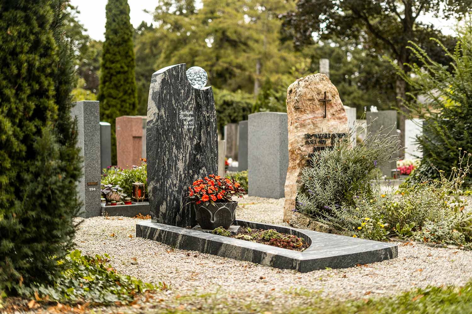 Ein einzeln stehendes Grab mit Grabstein und Blumen