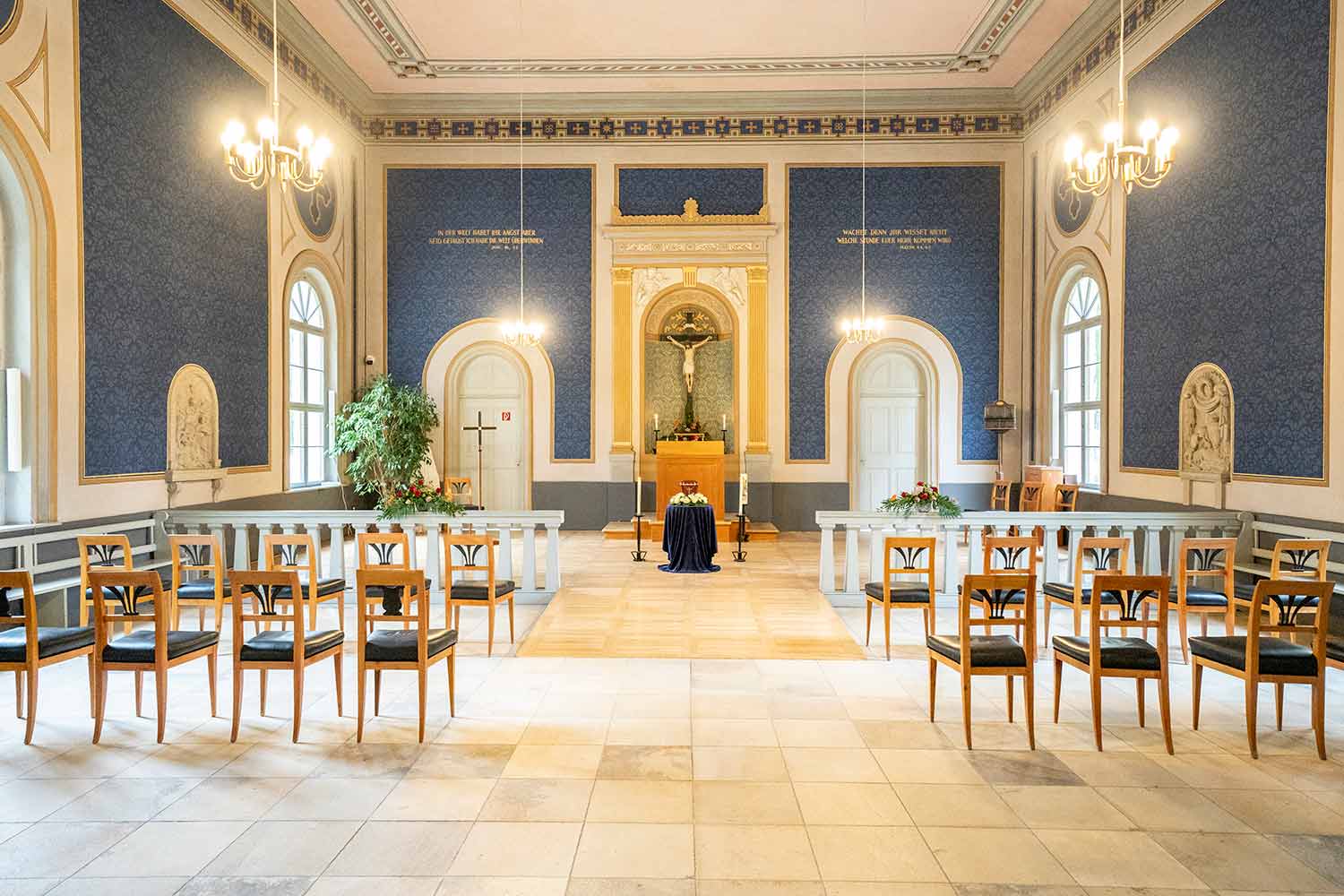 Leere Trauerhalle mit Stühlen, Kronleuchtern und einer Urne in der Mitte
